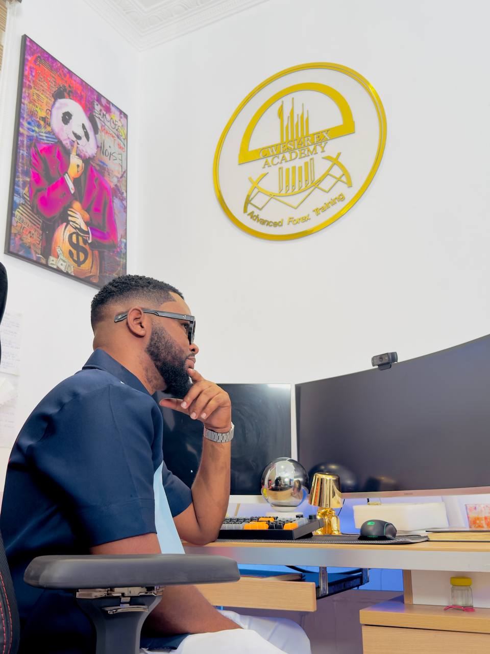 Cwesi4rex at his trading desk under the Cwesi4rex Academy crest